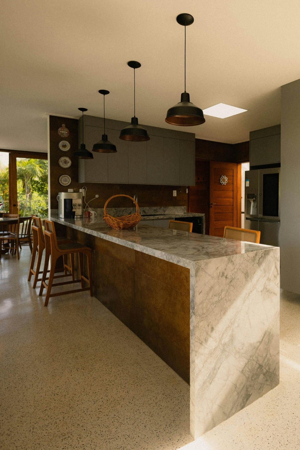 Cuisine contemporaine avec îlot central en bois clair, tabourets et hotte suspendue dans un intérieur résidentiel à Pointe-Calumet